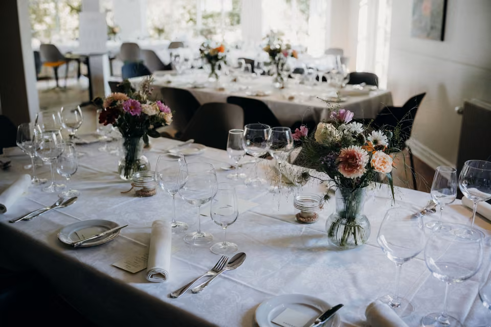 Tables de réception de mariage dressées avec fleurs et verres.