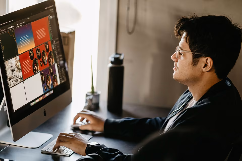 Graphiste travaillant sur des mises en page sur un grand écran de bureau.