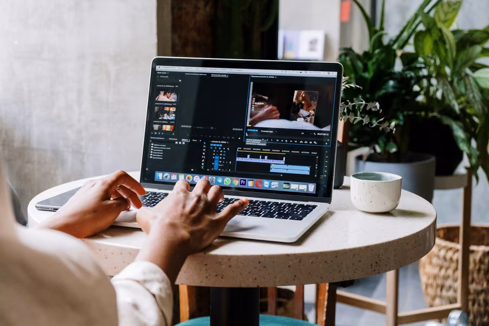 Mains montant une vidéo sur un ordinateur portable à une table ronde de café.