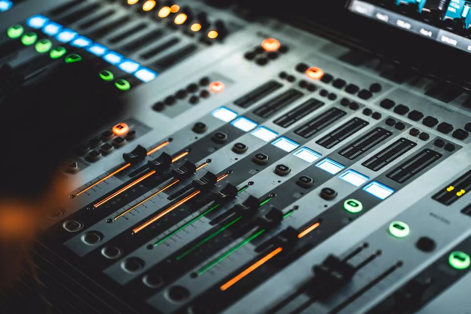 Faders éclairés et commandes de canaux sur une console de mixage audio.