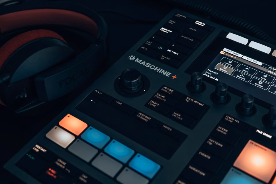 Contrôleur de production musicale avec pads lumineux, petits écrans et casque.