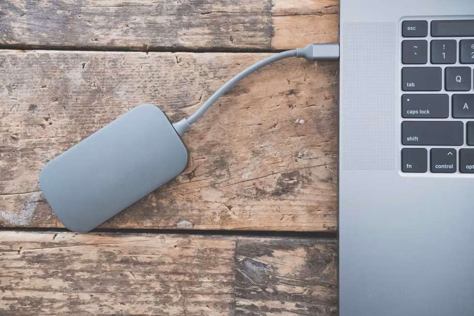 Disque externe branché à un portable sur un bureau en bois patiné.