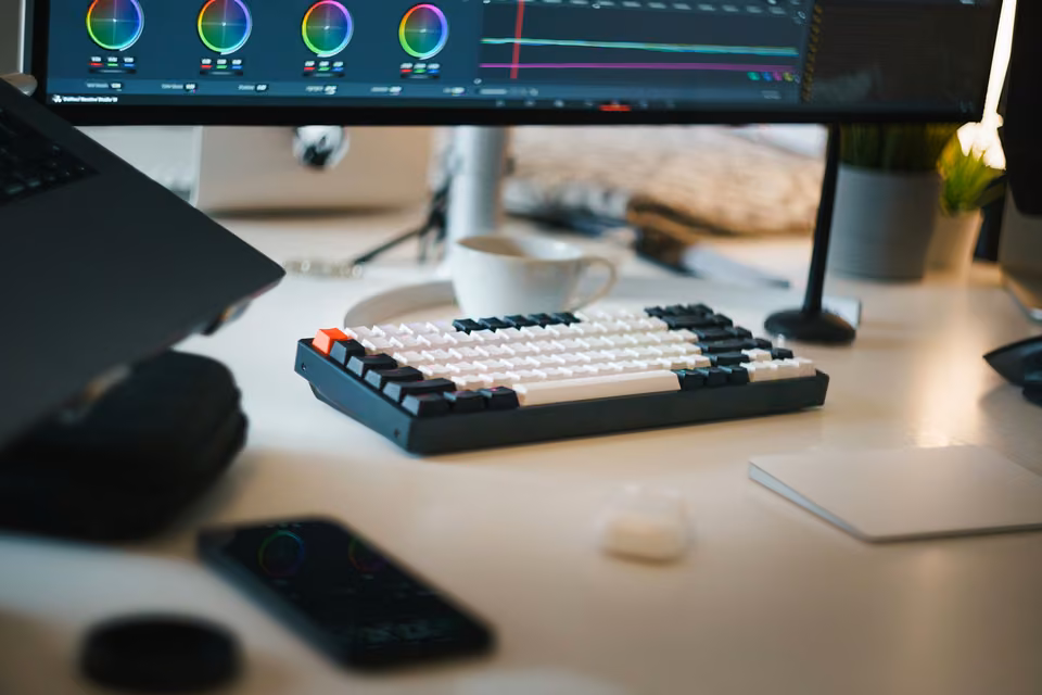 Bureau de montage avec clavier sous un écran affichant roues colorimétriques et courbes.