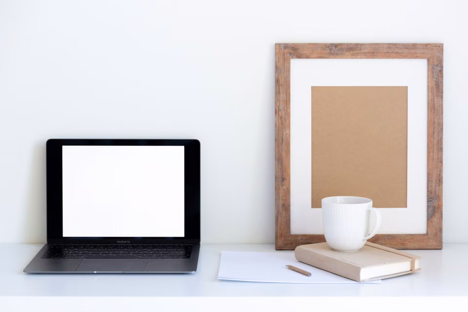 Bureau avec ordinateur portable, tasse et carnet.