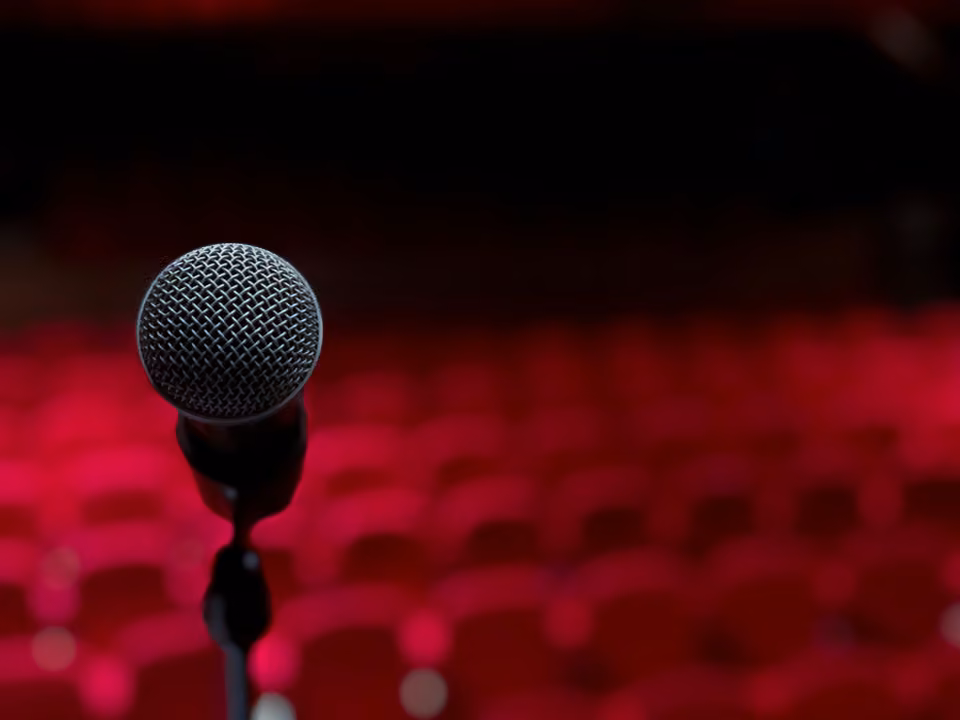 Micro devant les fauteuils rouges d’un auditorium vide.