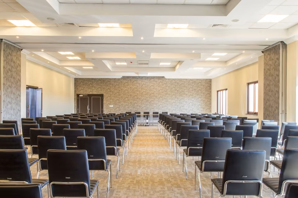 Salle de séminaire vide avec rangées de sièges.