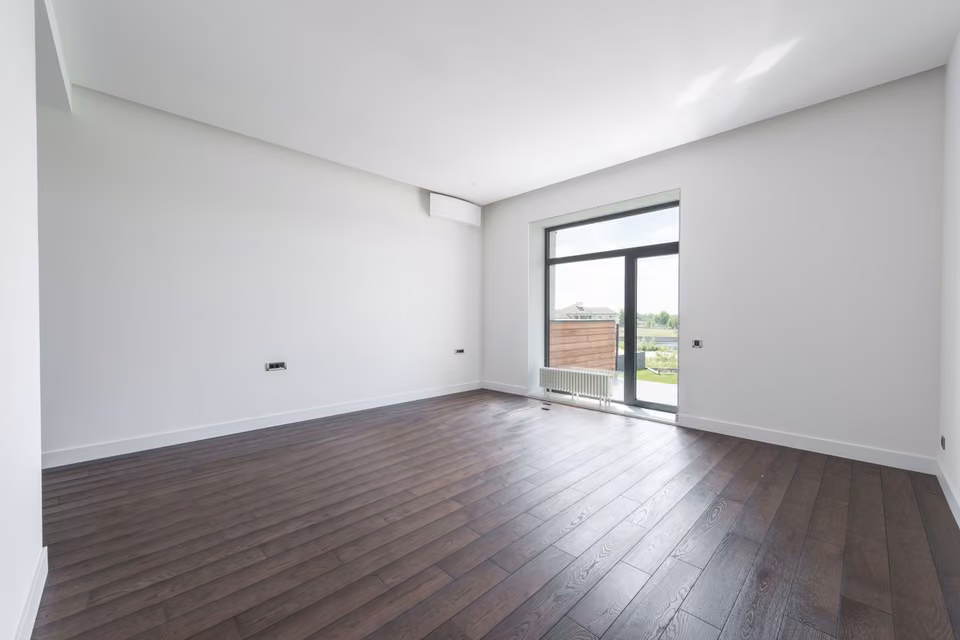 Pièce vide avec parquet sombre et porte de balcon