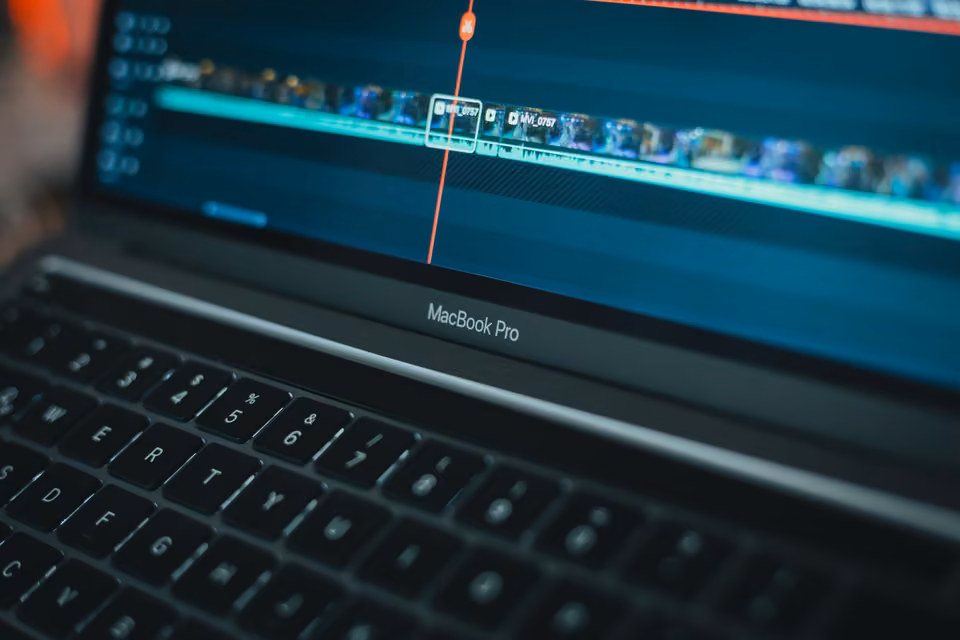 Clavier de MacBook Pro sous une timeline vidéo avec une tête de lecture rouge.