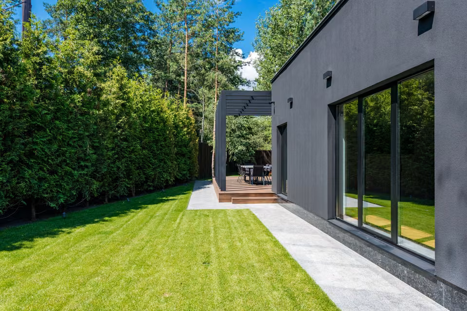 Façade moderne sur jardin avec pelouse et haie