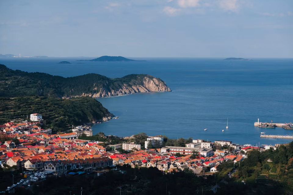 Ville côtière aux toits rouges face à la mer.