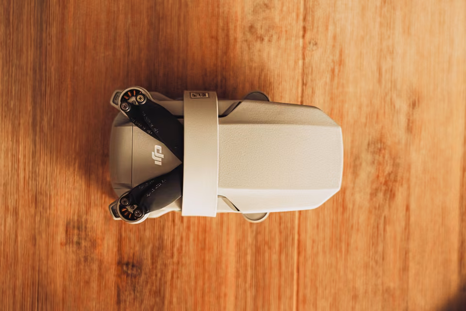 Petit drone replié sur une table en bois.