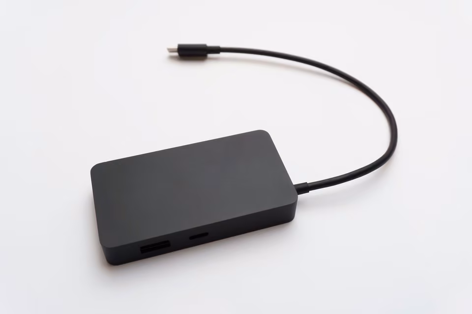 Hub USB-C compact avec emplacements de cartes mémoire et ports de connexion sur une surface blanche.