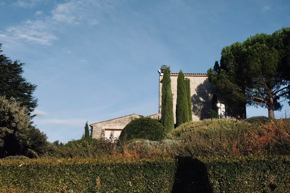 Maison en pierre en Provence, entourée de végétation.