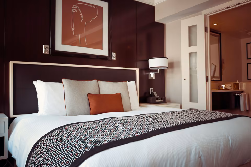 Chambre d’hôtel avec lit blanc et mur bordeaux