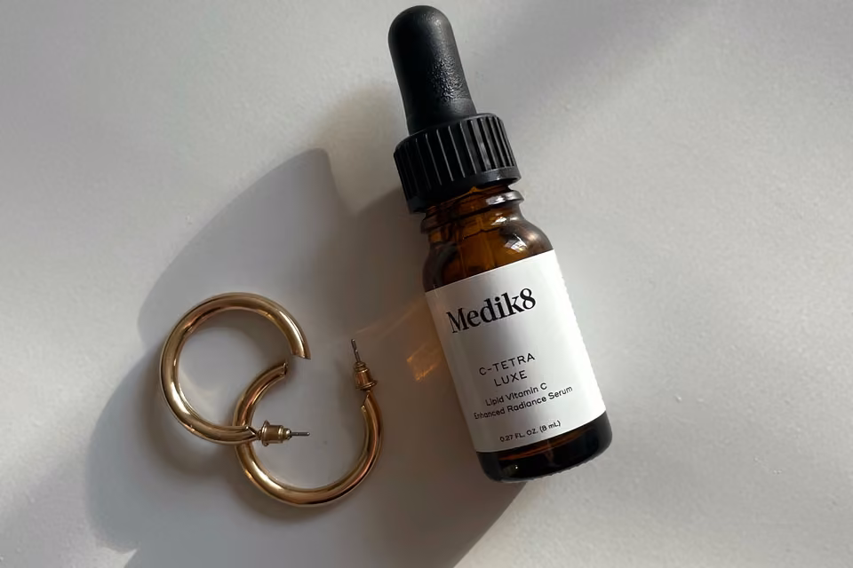 Flacon de sérum et bijoux éclairés naturellement.