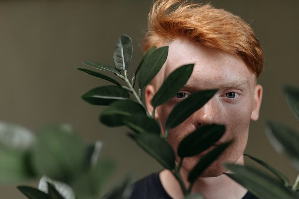 Portrait d’un homme roux derrière des feuilles