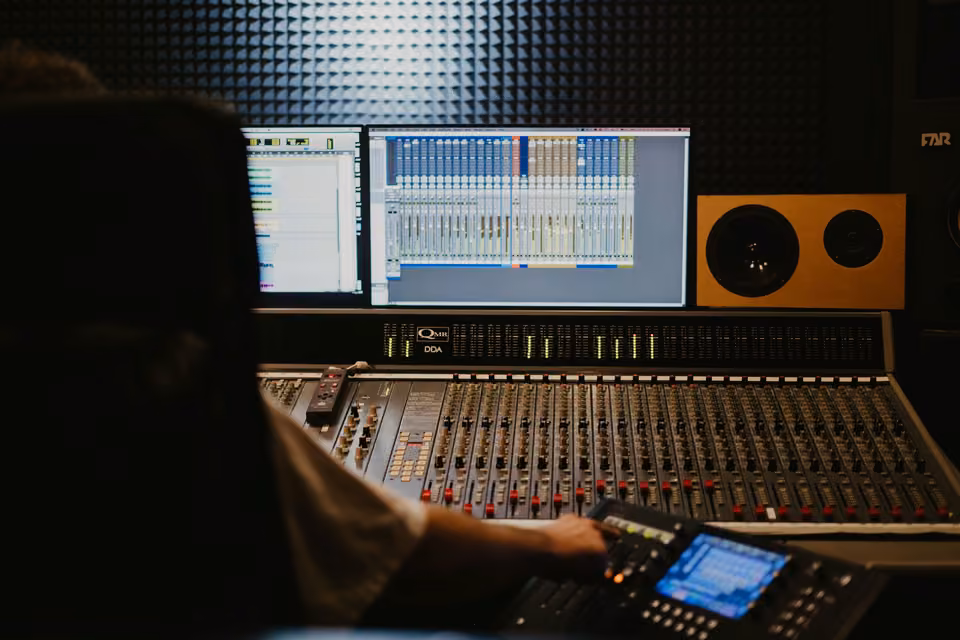 Console de studio sous deux écrans affichant un logiciel de production audio.