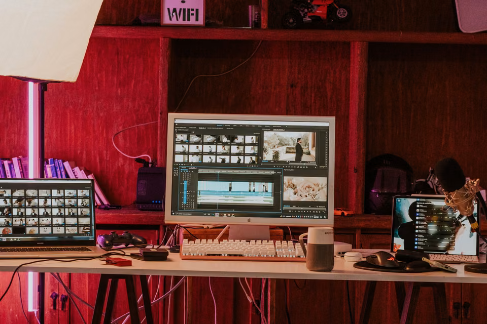 Timelines vidéo sur deux écrans dans un studio de montage à la lumière chaude.