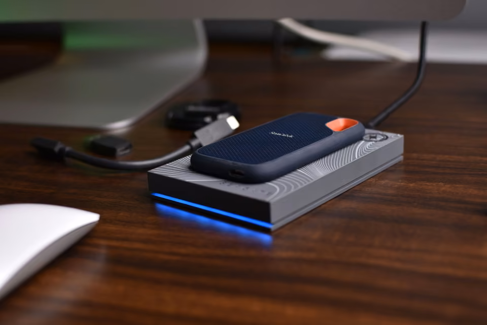 SSD portable branché par câble sur un bureau en bois.