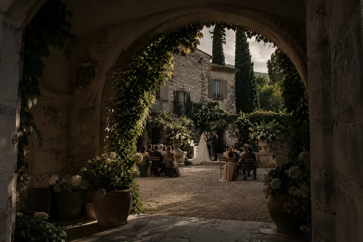 Une cérémonie de mariage dans le jardin d’une demeure en pierre.